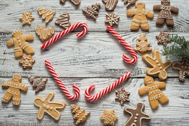 Biscoito de Natal e doces na madeira, vista superior dos alimentos. Presentes com papel artesanal. Texto.