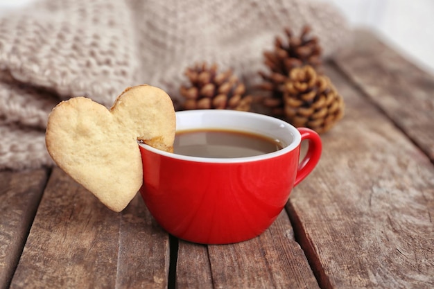Biscoito em forma de coração na xícara de café na mesa de madeira closeup