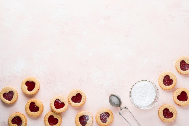 Foto biscoito linzer tradicional com geléia de morango e açúcar em pó no fundo bonito rosa vista superior comida tradicional sobremesa doce austríaca caseira no conceito de lanche de feriado do dia dos namorados