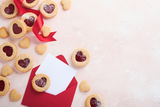 Biscoito Linzer tradicional com geléia de morango e presente de açúcar em pó e fita vermelha no fundo rosa bonito Vista superior Comida tradicional sobremesa doce austríaca caseira no dia dos namorados