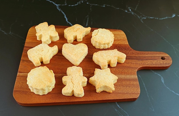 Biscoitos caseiros assados frescos na tábua de pão de madeira isolada no pano de fundo preto