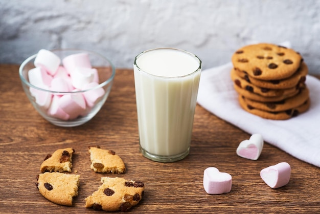 Biscoitos caseiros com leite e marshmallow de ar na toalha de cozinha e mesa de madeira Bom dia Conceito de café da manhã
