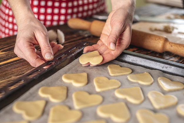 Biscoitos caseiros crus em forma de coração em uma assadeira para assar