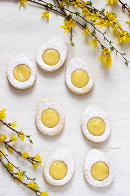 Biscoitos caseiros do limão da Páscoa e galhos de florescência da forsítia em um fundo claro.