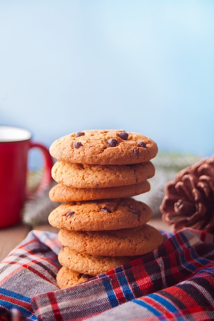 Biscoitos com caneca vermelha de chocolate quente, cone na mesa de madeira