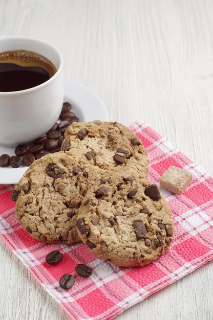 Biscoitos com chocolate e café quente em uma mesa de madeira leve