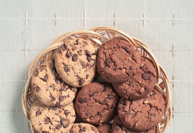 Biscoitos com chocolate e nozes em prato de vime na vista superior da toalha de mesa