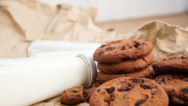 Biscoitos com gotas de chocolate em papel artesanal e garrafas de leite. Cobras orgânicas artesanais naturais para café da manhã saudável