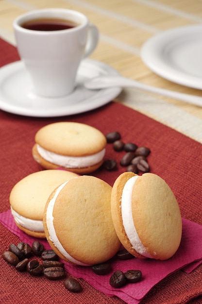 Biscoitos com marshmallows e café numa toalha de mesa vermelha