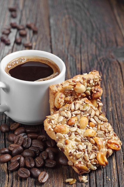 Biscoitos com nozes diferentes e xícara de café quente na velha mesa de madeira