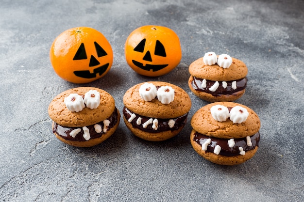 Foto biscoitos com pasta de chocolate em forma de monstros e tangerinas de abóbora para o halloween