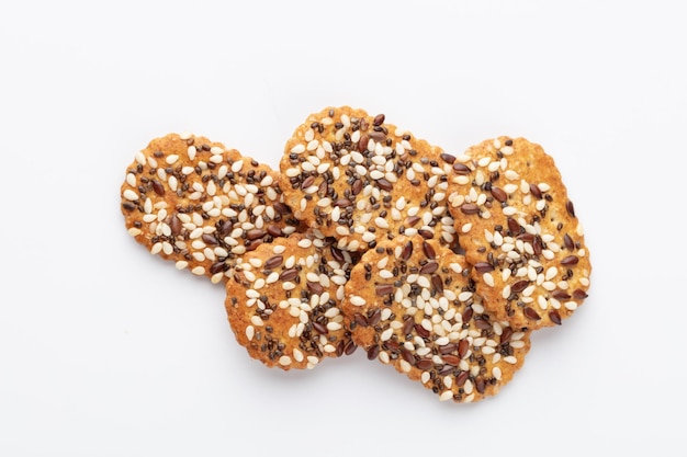 Biscoitos crocantes salgados com gergelim, sementes de girassol isoladas no fundo branco.