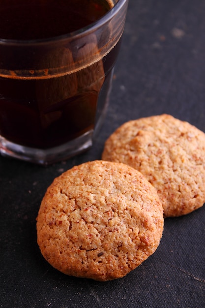 Foto biscoitos de amêndoa em um fundo preto com uma xícara de café