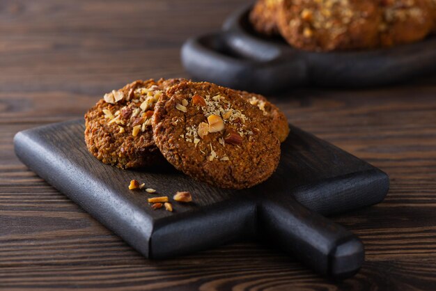 Biscoitos de aveia caseiros com cenouras, nozes e quinua em uma placa de madeira. Sem açúcar, sem glúten e sem lactose e vegano.