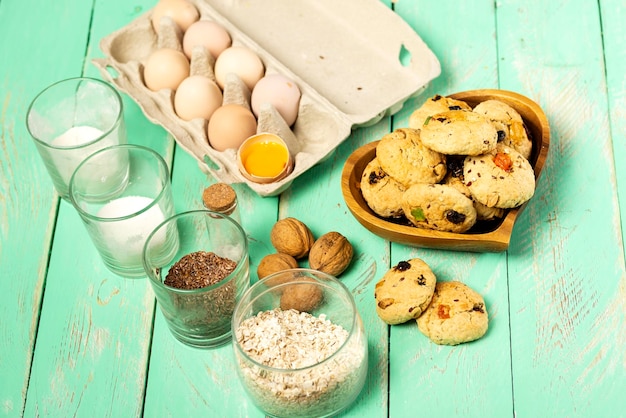 Biscoitos de aveia com frutas cristalizadas em uma placa de madeira e ingredientes para sua preparação