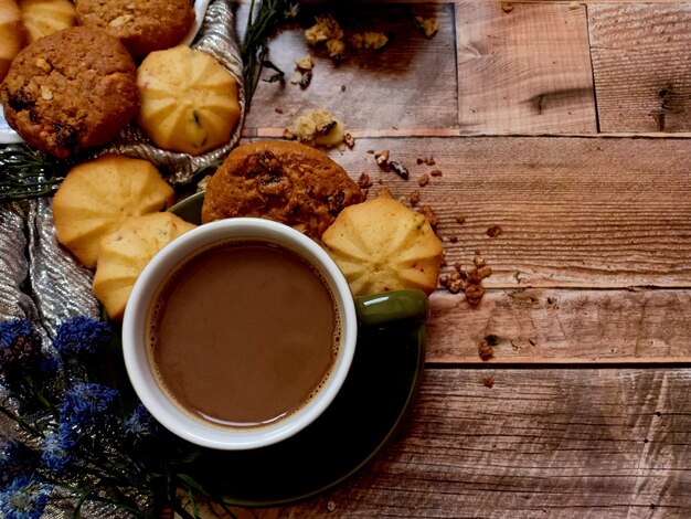 Biscoitos de aveia com passas e biscoitos de frutas com uma xícara de café quente no fundo de madeira