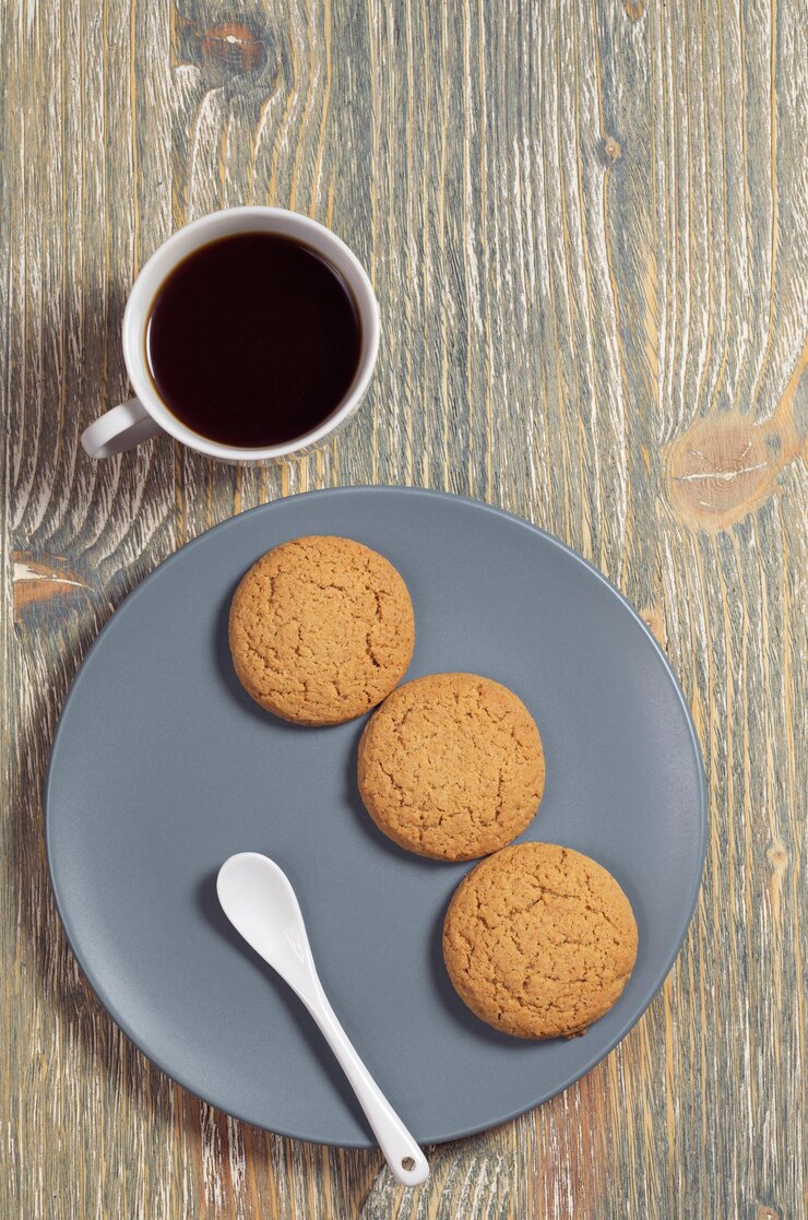 Biscoitos de aveia em chapa cinza e xícara de café no antigo fundo de madeira, vista superior