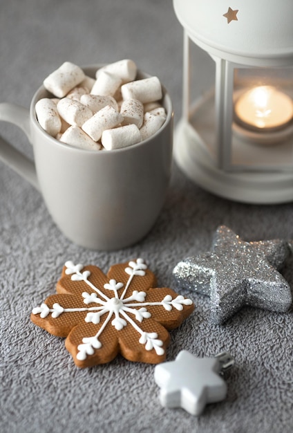 Biscoitos de biscoito de gengibre no candeeiro de mesa com velas e uma xícara cinza de cacau com marshmallow