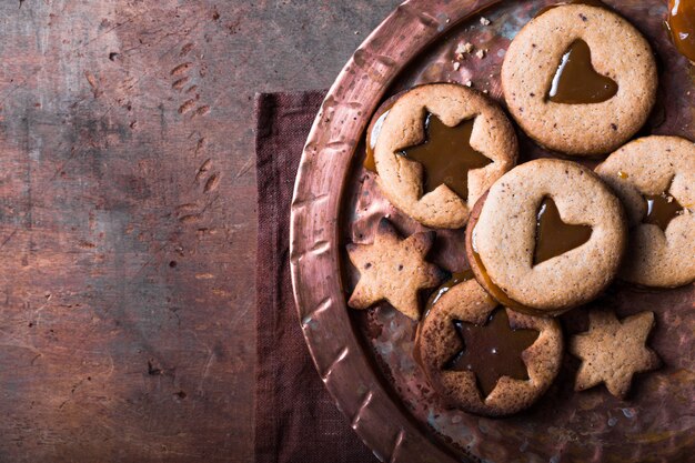 Biscoitos de caramelo caseiros da forma da estrela do ano novo do Natal sobre o fundo de madeira. Postura plana, espaço.