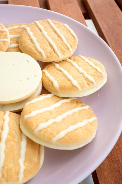 Foto biscoitos de chocolate branco com limão e laranja em um prato rosa em uma mesa de café