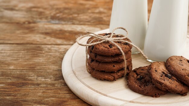 Biscoitos de chocolate caseiros e leite sobre fundo de madeira em estilo rústico. Lanche doce