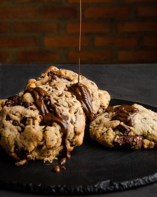 Biscoitos de chocolate com calda de chocolate, em fundo preto e parede de tijolos