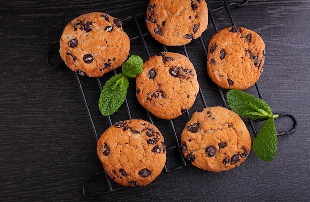 Foto biscoitos de chocolate decorados com hortelã em um fundo escuro, vista superior.