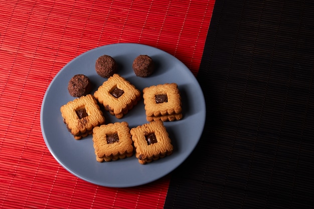 Foto biscoitos de chocolate empilhados em uma placa cinza na mesa de madeira vermelha e preta