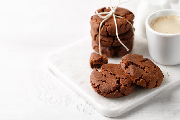 Biscoitos de chocolate no café da manhã com uma xícara de café em uma placa de mármore branca