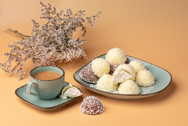 biscoitos de coco em um prato verde com uma xícara de café em um fundo laranja