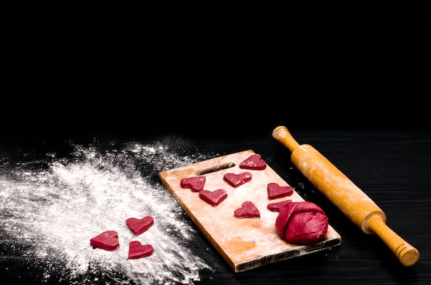 Biscoitos de coração vermelho em uma mesa preta, assando no dia dos namorados