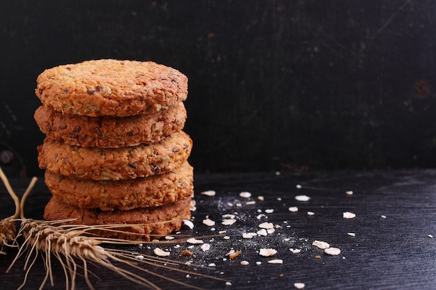 Biscoitos de farinha de aveia com grões em um fundo preto. foco seletivo.