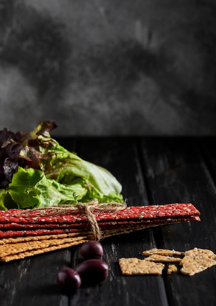 Biscoitos de farinha de beterraba e centeio com legumes para fazer lanches em uma parede preta. vegetarianismo e alimentação saudável