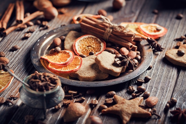 Biscoitos de gengibre caseiros, especiarias e decorações em fundo de madeira. Conceito de férias sazonais.