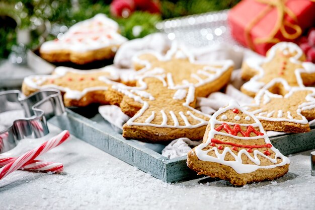 Biscoitos de gengibre caseiros tradicionais de natal com glacê ornamentado. homem-biscoito, anjo, sino com decorações de natal sobre a superfície branca do bokeh.