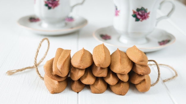 Biscoitos de gengibre com uma xícara de café em uma mesa de madeira branca.