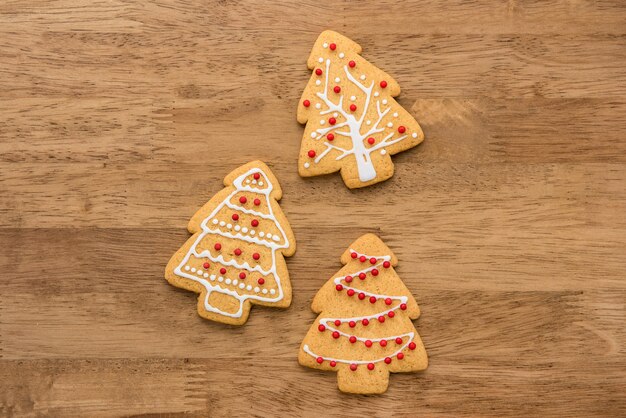 Biscoitos de gengibre de forma de árvore de Natal em fundo de madeira