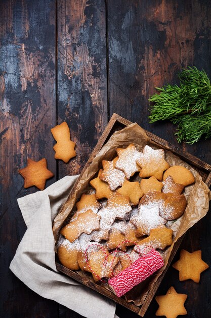 Biscoitos de gengibre de forma de estrela de Natal caseiros em caixa de madeira na superfície de madeira velha. Vista do topo