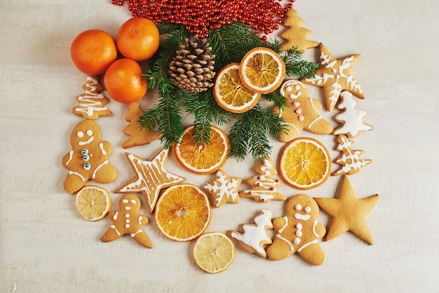 Biscoitos de gengibre de Natal e laranja seca e especiarias na mesa branca. Cadeiras Árvores de Natal, cones e decorações de Natal