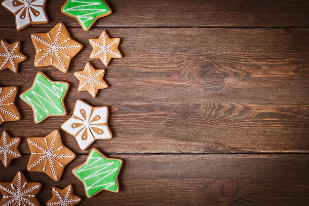Biscoitos de gengibre de Natal em forma de estrelas encontra-se em um fundo de madeira.