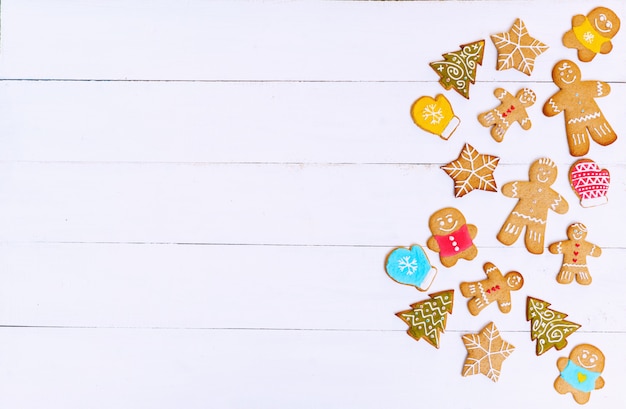 Biscoitos de gengibre em forma de homens, estrelas e árvores de saco e superfície de madeira branca. Conceito de natal