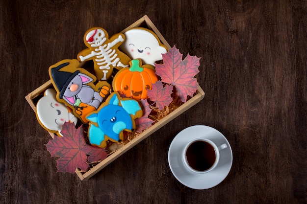 Biscoitos de gengibre engraçado para o halloween. bolos de férias estão em uma caixa ao lado de uma xícara de chá.