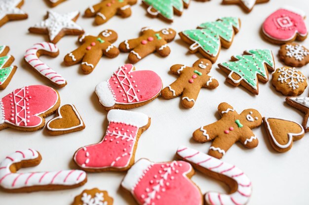 Biscoitos de gengibre festivos feitos à mão em forma de estrelas flocos de neve pessoas meias luvas de funcionários corações de árvores de natal para férias de natal e ano novo em fundo de papel branco