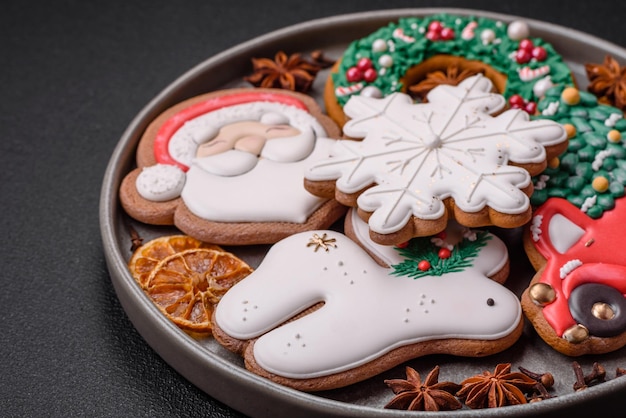 Biscoitos de gengibre frescos e deliciosos de Natal ou ano novo com padrão temático de cor brilhante em fundo escuro de concreto