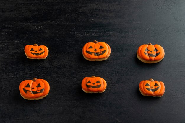 Biscoitos de gengibre laranja para o halloween na forma de uma abóbora encontram-se horizontalmente sobre uma mesa escura. cookie sorridente. vista do topo