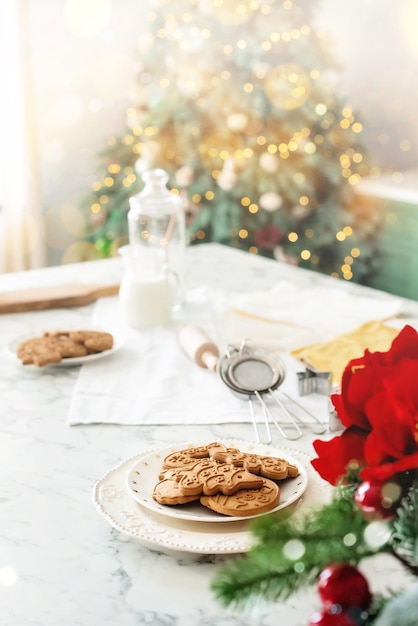 Biscoitos de gengibre na cozinha decorada perto da árvore de Natal. Fundo vertical