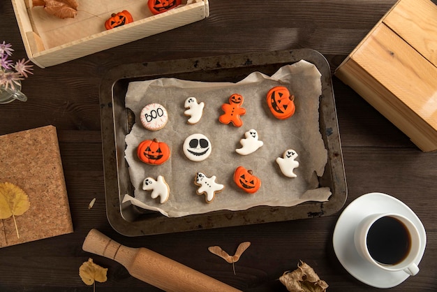 Biscoitos de gengibre para o halloween estão em uma forma de madeira xícara de café e pão de gengibre na mesa vista superior