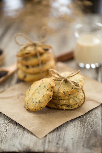 Biscoitos de gergelim, gergelim e leite em fundo preto de madeira