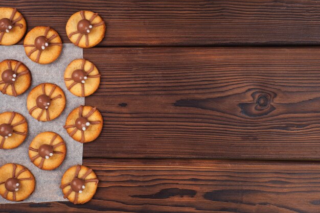 Biscoitos de Halloween com decorações engraçadas na mesa da cozinha de madeira, copie o espaço