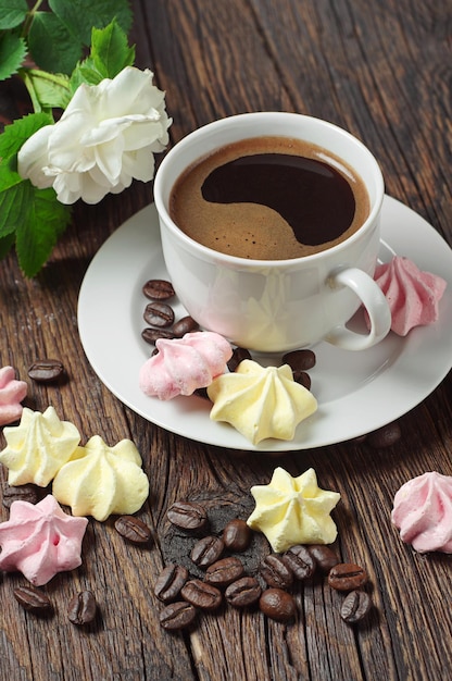 Biscoitos de merengue e café quente na velha mesa de madeira